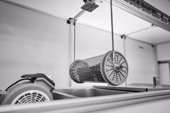 Metallkorb mit 3D geruckten Bauteilen an Portalroboter über Färbeanlage